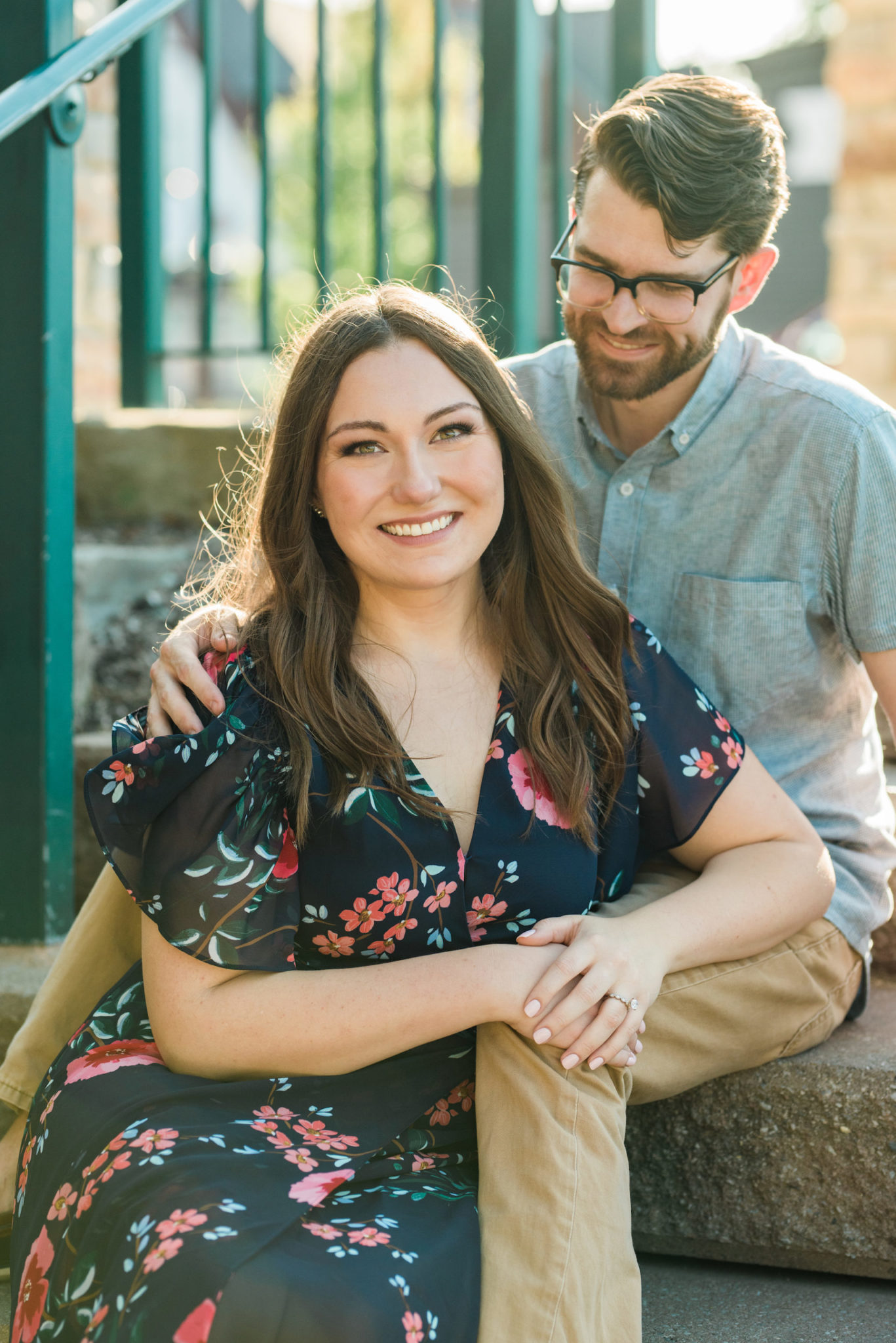 A portrait of a couple sitting on stones and smiling at the camera.