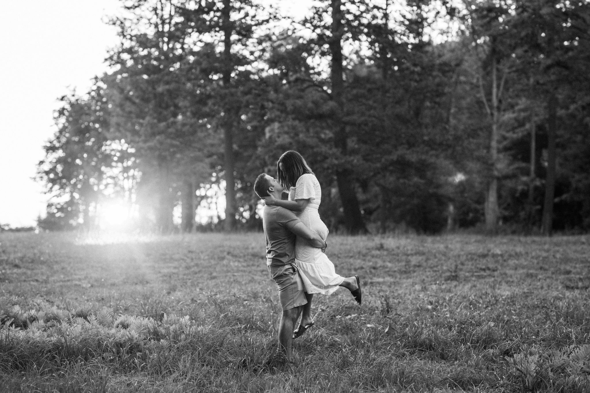 Black and white image of a guy picking up a girl in a field in South haven, MI.