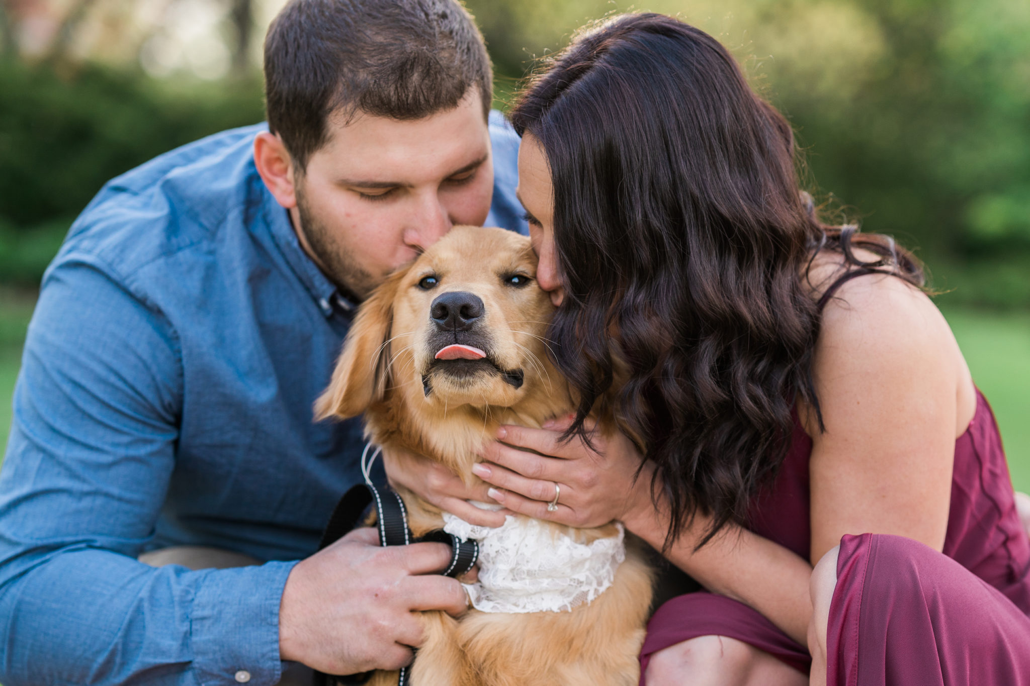 a couple kissing their golden retriever during their engagement photo session in east lansing