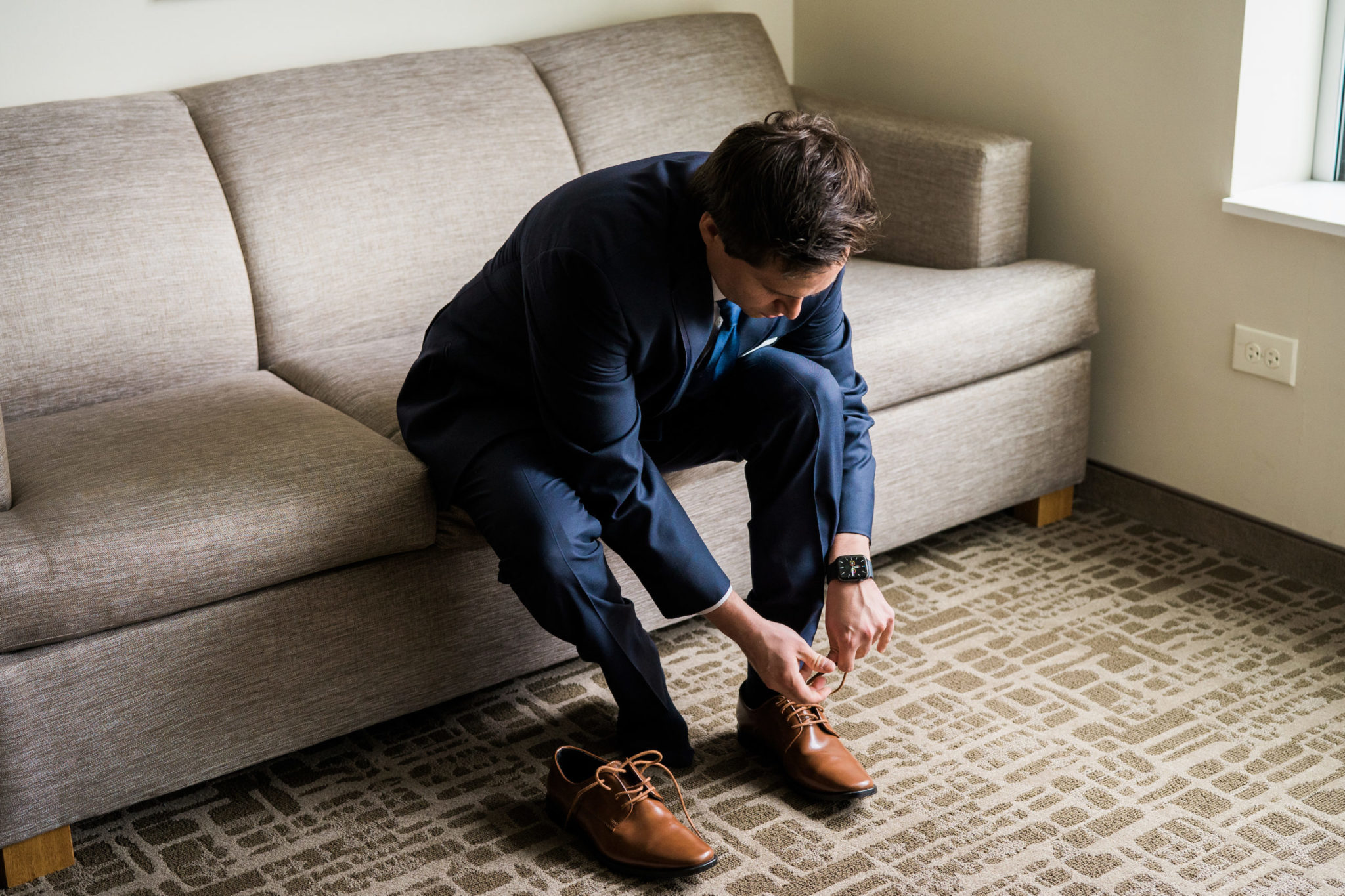 a groom tying his shoes before his downtown detroit wedding