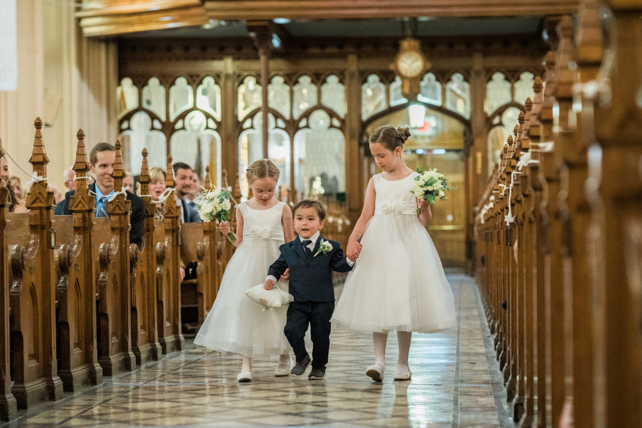 ring bearer and flower girls walking down the processional at the basilica of sainte anne de detroit wedding ceremony