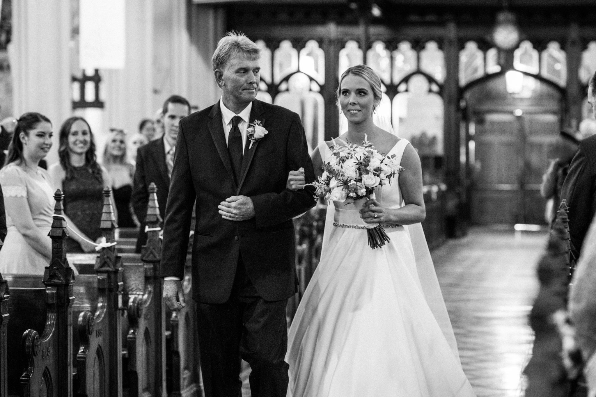 the bride and her father walking down the aisle of the basilica of sainte anne de detroit at the start of the wedding ceremony processional,downtown detroit wedding day