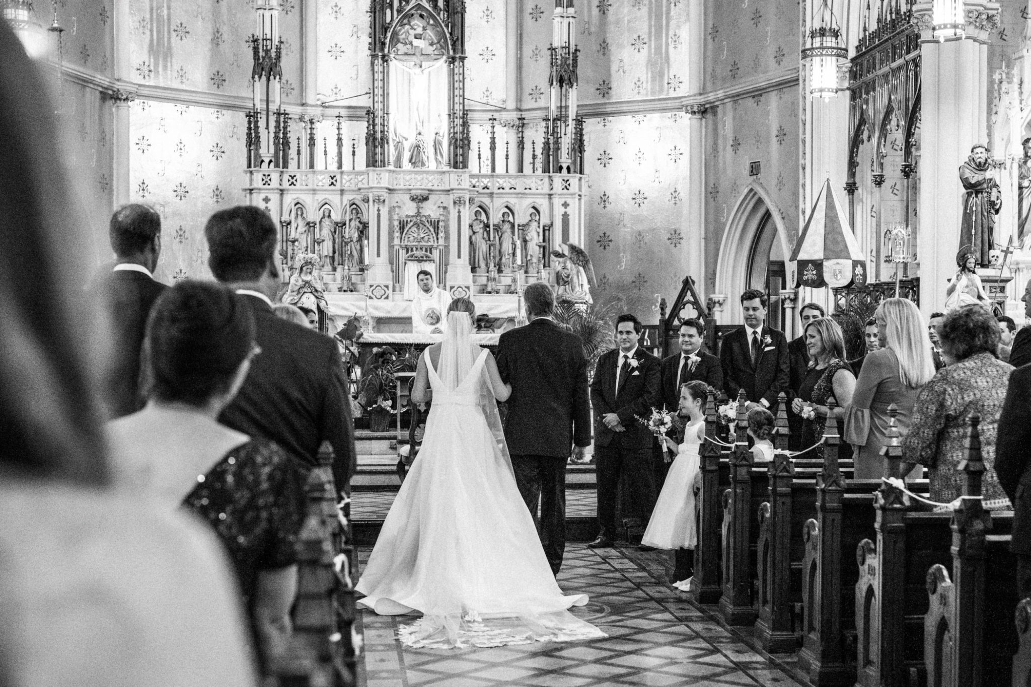 the bride and her father walking down the aisle of the basilica of sainte anne de detroit at the start of the wedding ceremony processional,downtown detroit wedding day