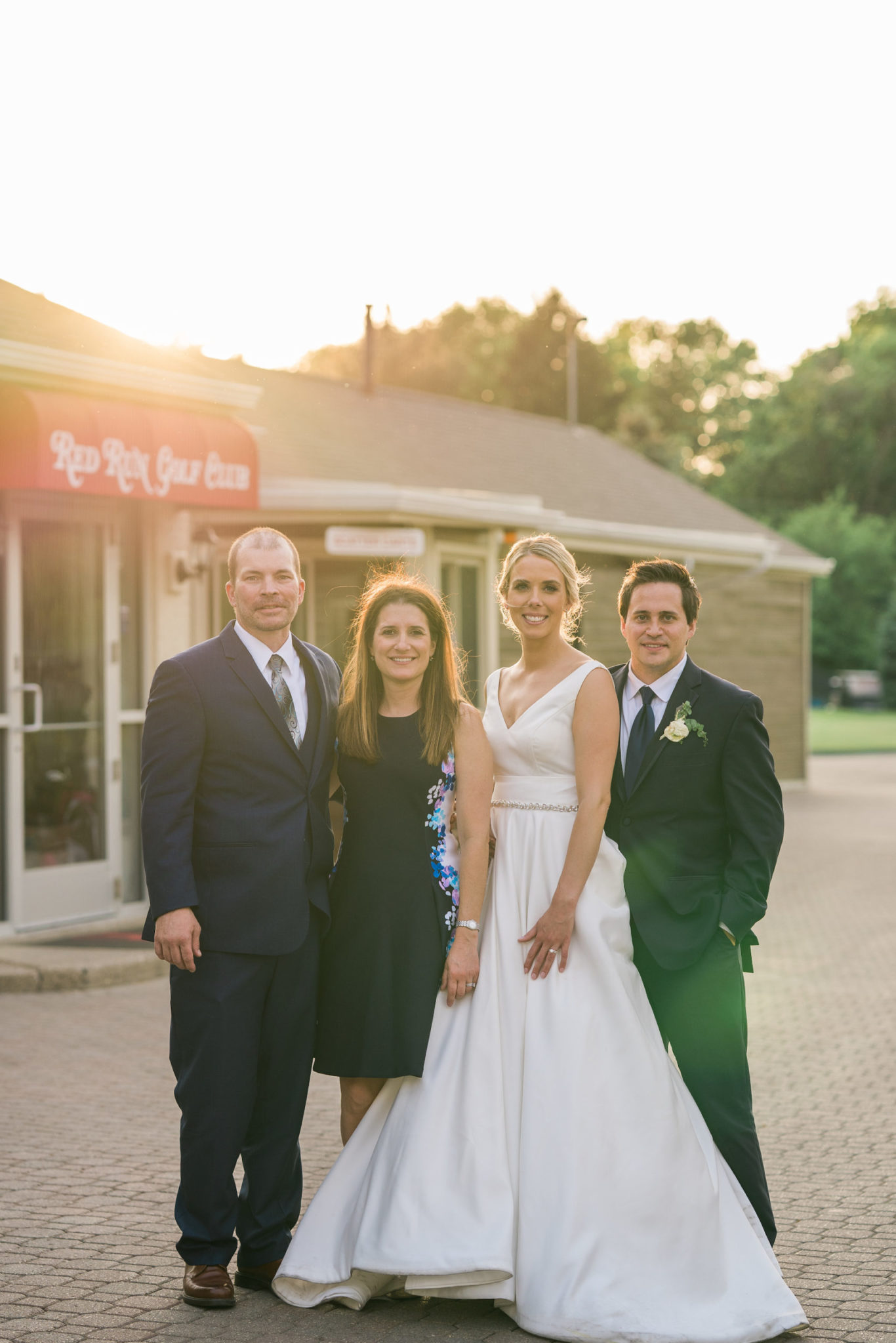 a bride and groom photographed with a wedding guest couple during golden hour at the red run golf course in royal oak michigan