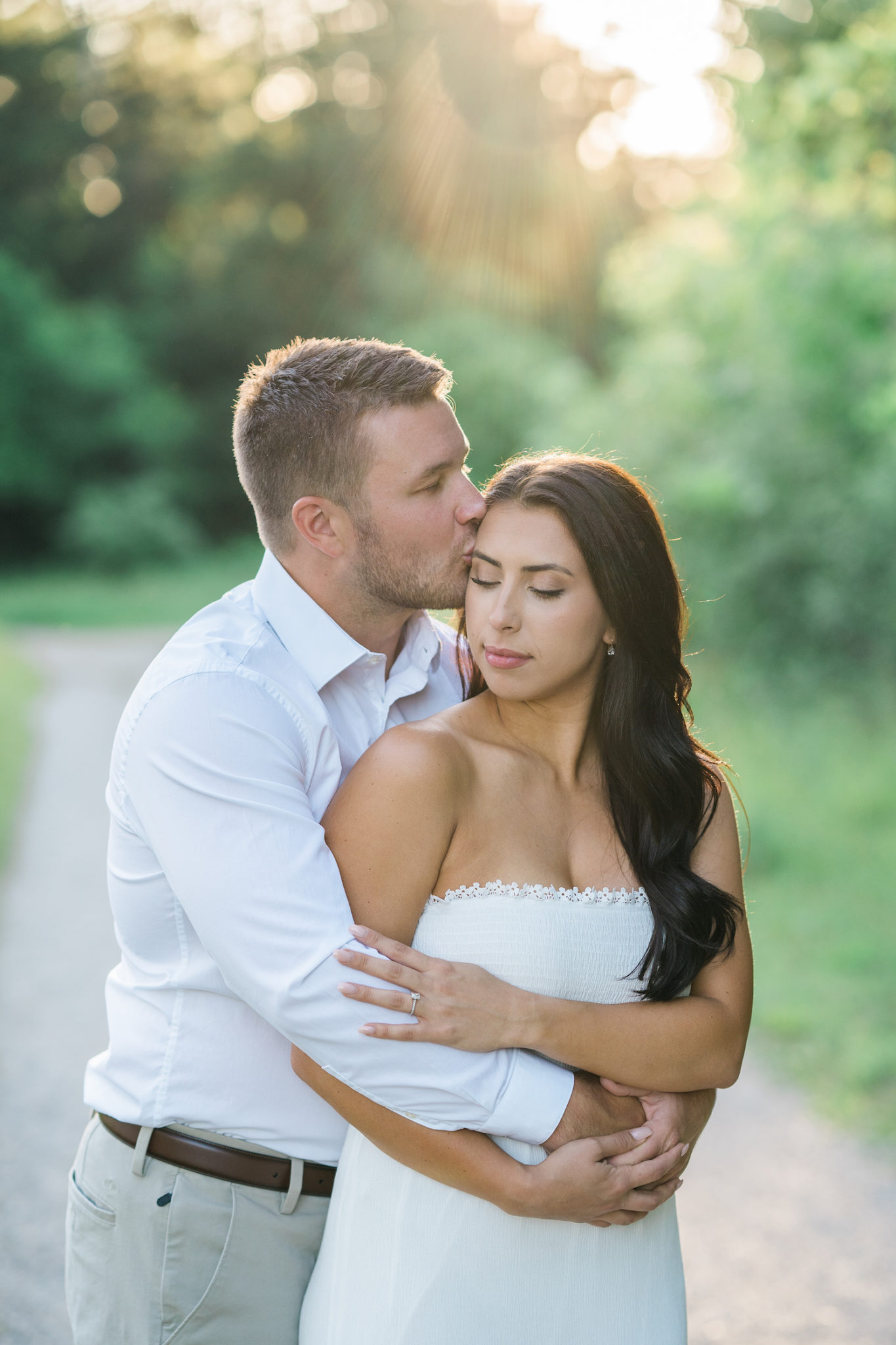 a couple embracing and kissing during their engagement session at golden hour in stoney creek metro park