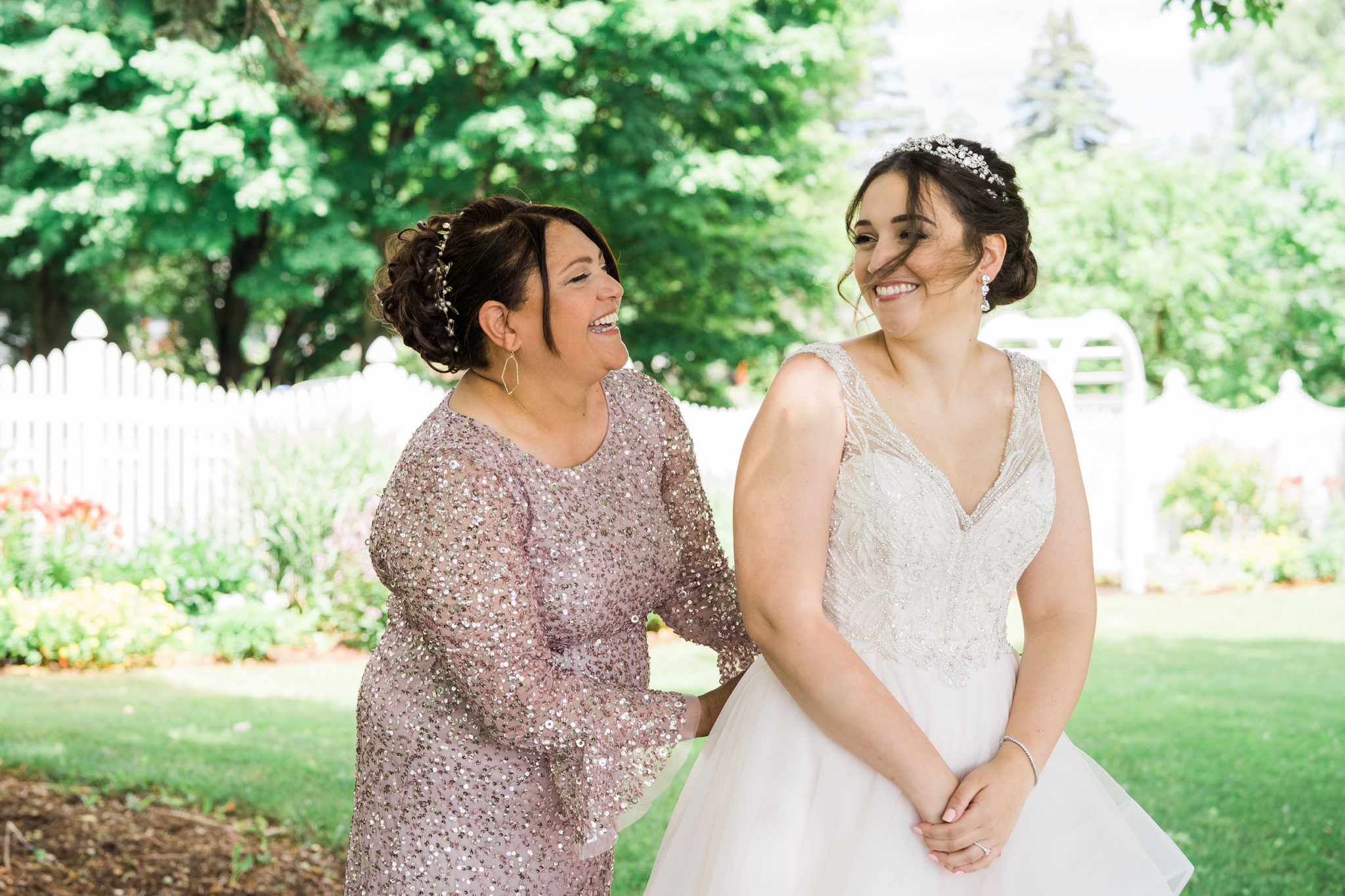 mother of the bride in an adrianna papell dress helping the bride button her justin alexander wedding dress