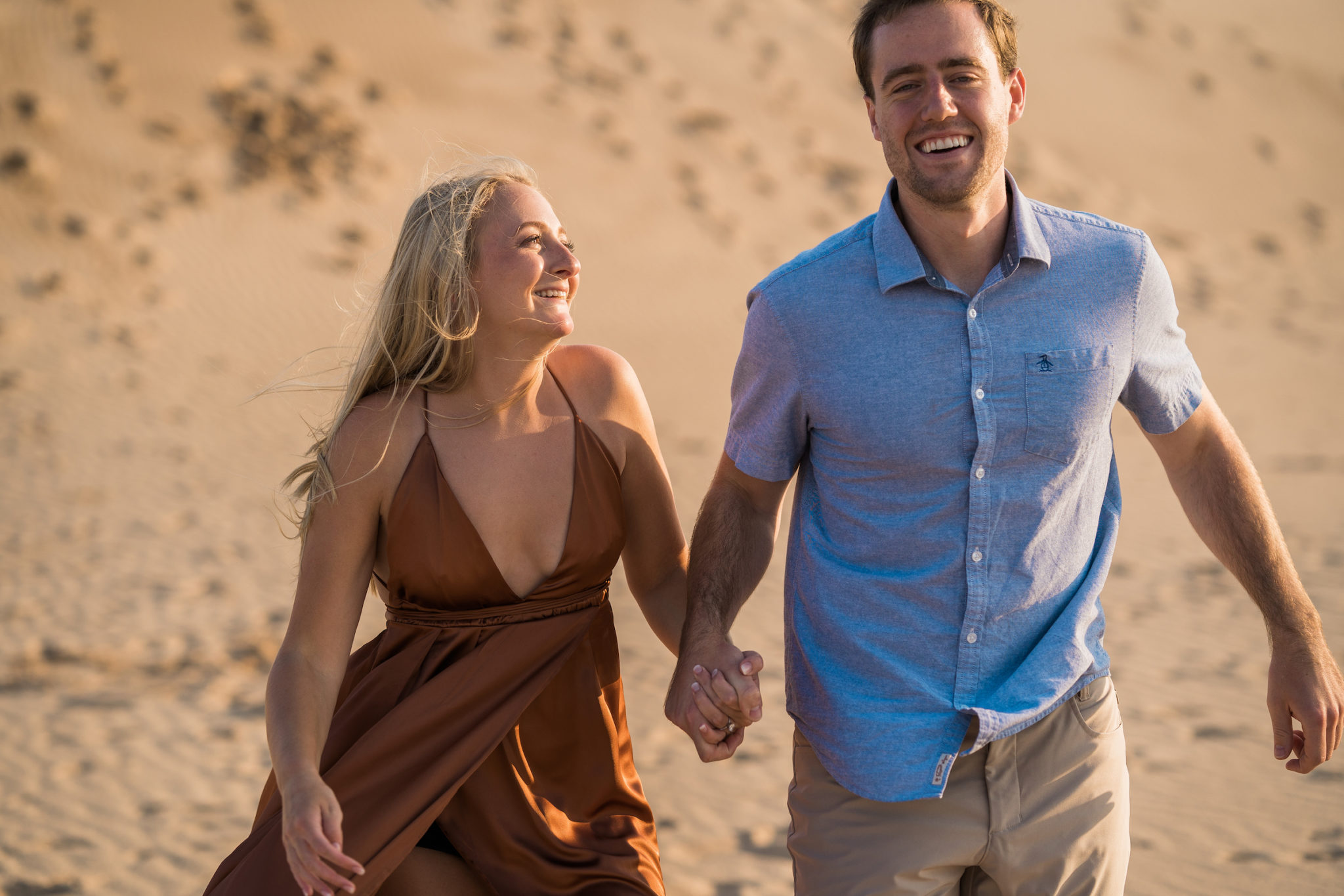 a couple running down the sand dunes at silver lake during their engagement photos