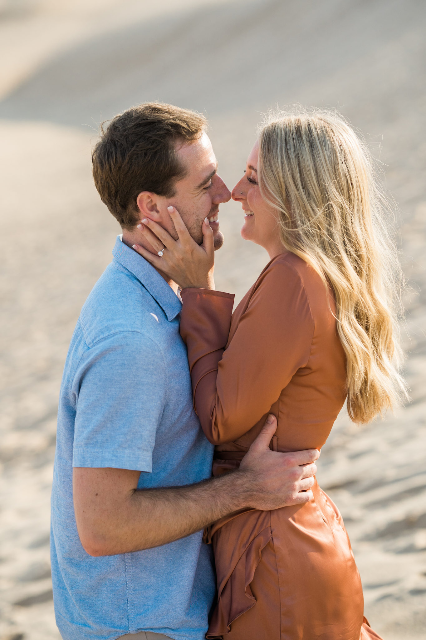 a couple embracing during their sand dune engagement photo session in summer in michigan