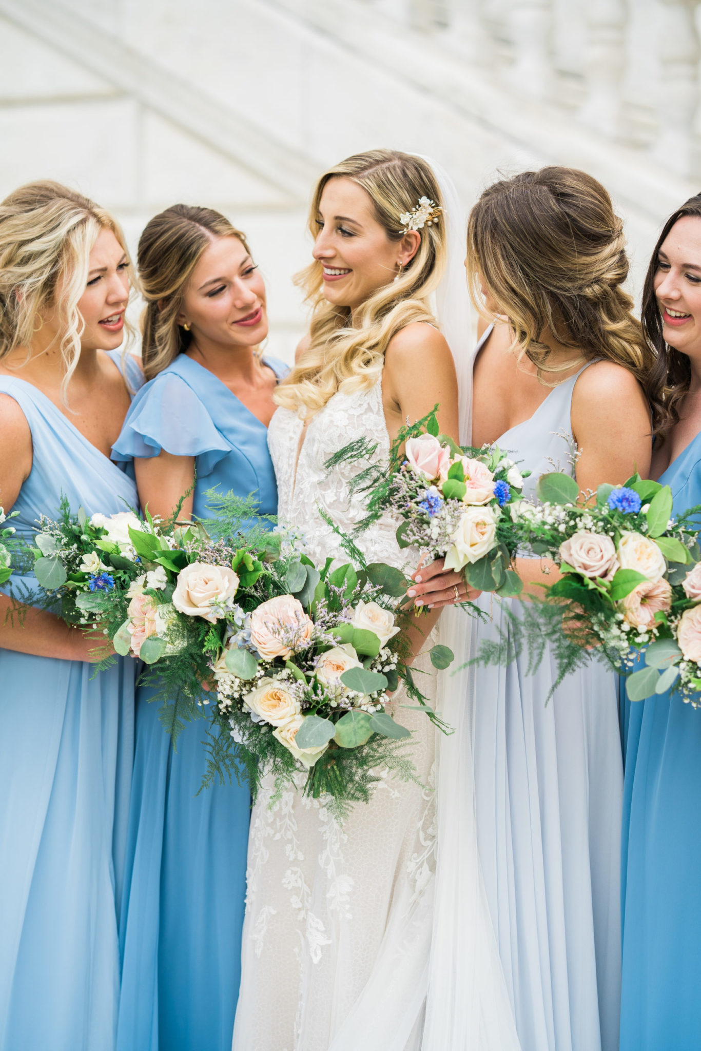 a bride and bridesmaids holding flowers and smiling at her downtown detroit wedding