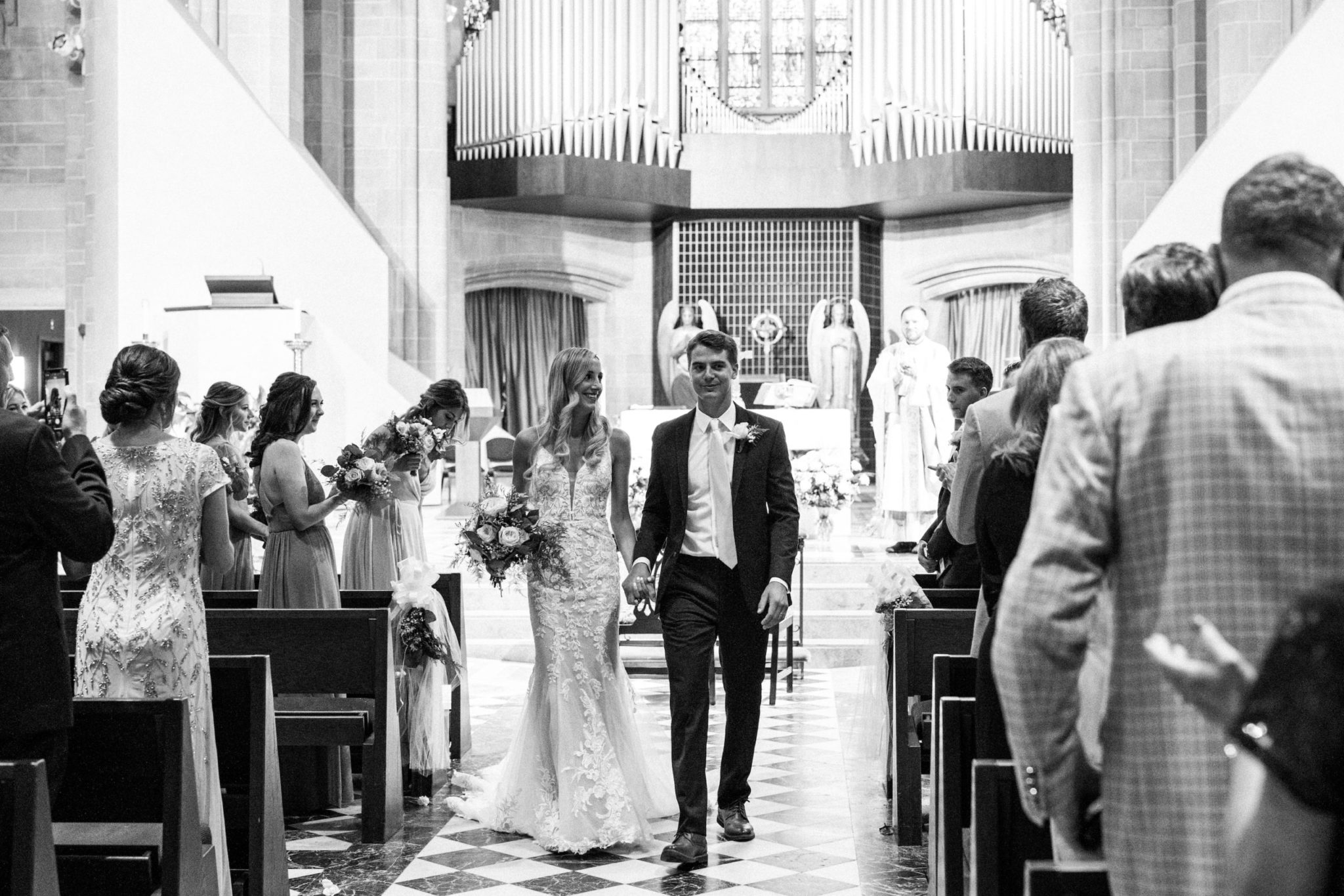 a bride and groom walking out of the church during their downtown detroit ceremony