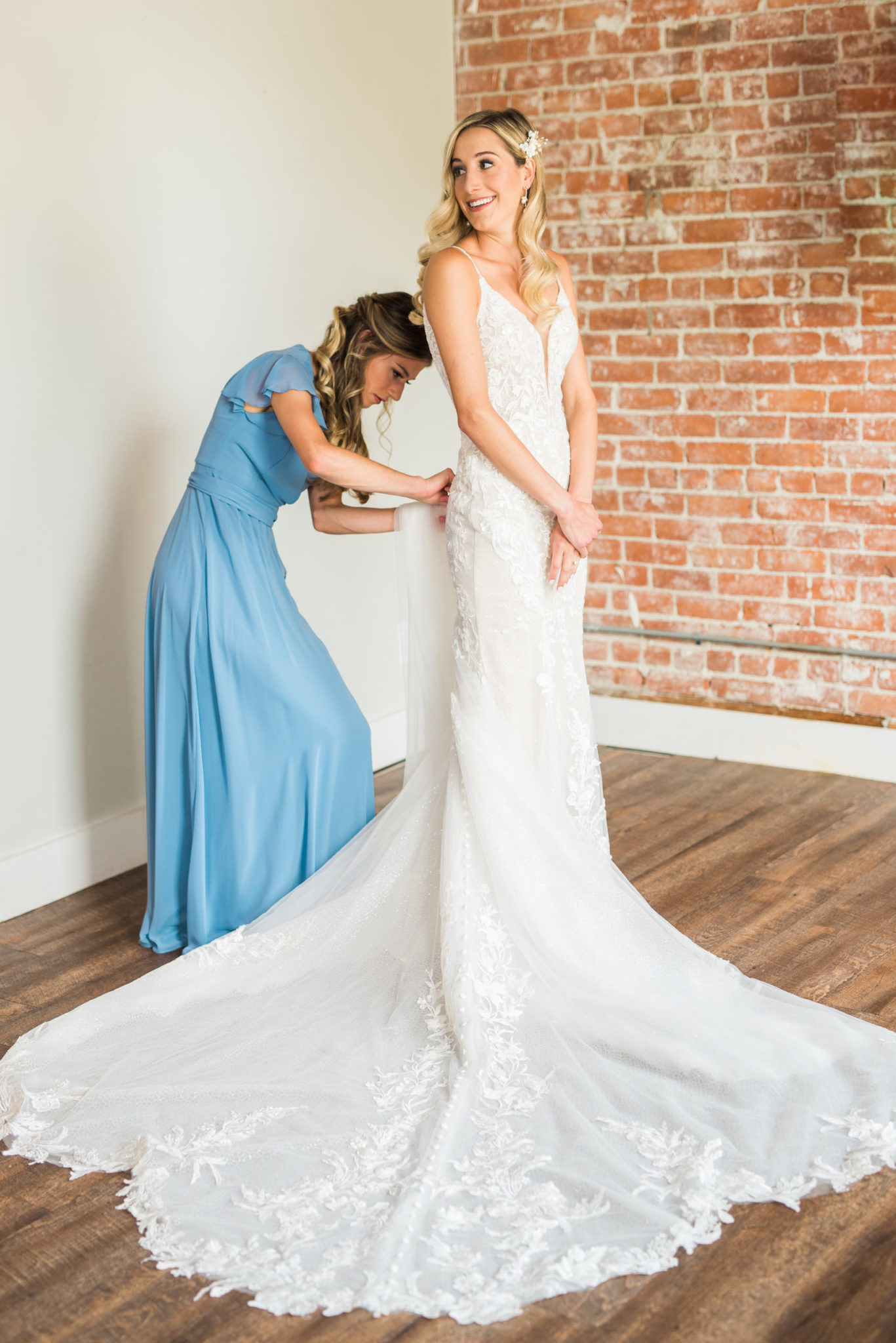 a bridesmaid helping the bride get dressed on her classic wedding day in detroit michigan
